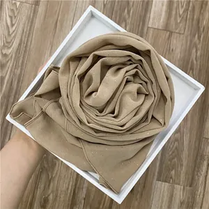 Détail d'un châle en mousseline beige à paillettes dorées montrant la texture du tissu