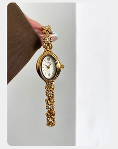 Close-up of golden floral bracelet watch with oval dial and diamond embellishments