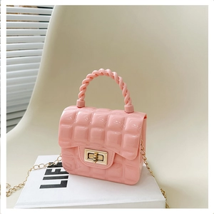 Detailed view of pink quilted jelly bag with metal turn-lock and woven handle on white prop