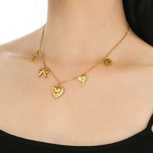 Detail of gold titanium necklace featuring bow, cross, and heart shaped charms