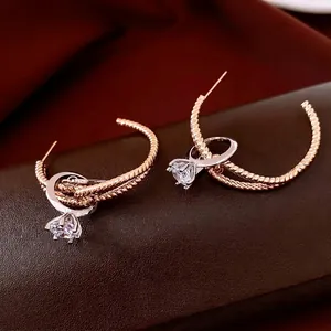 Rose gold C-shape rope twist earrings with silver zircon ring pendant on leather background