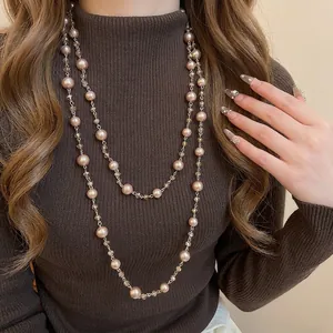 Elegant layered pearl necklace with champagne beads on a brown sweater for a retro style
