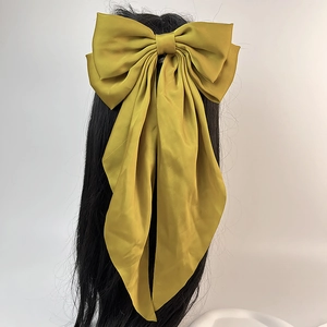 Vue détaillée d'une grande barrette à nœud papillon en satin jaune moutarde à rubans