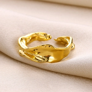Golden irregular heart ring with molten texture on soft beige silk fabric background
