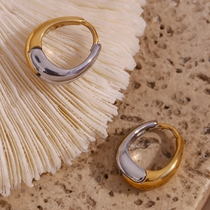 Macro view of bicolor 18K gold and silver plated pear-shaped hoop earrings on stone