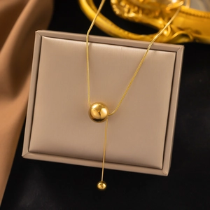 Detail of 18K gold-plated snake chain necklace with double spherical pendants on jewelry box