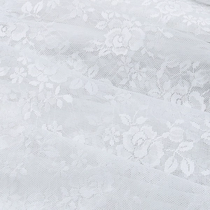 Vue macro détaillée du tissu en dentelle blanche avec motifs floraux et texture en maille