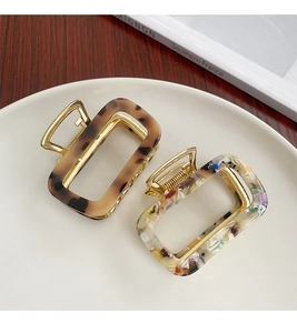 Detailed close-up of two acetic acid claw clips with leopard and terrazzo patterns