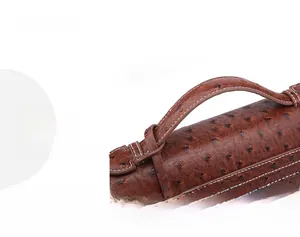 Detail of brown ostrich pattern leather bag with white contrast stitching and top handle