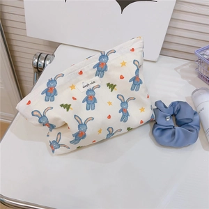 Detail of cute blue rabbit print on a cream cotton makeup bag with blue hair tie accessory