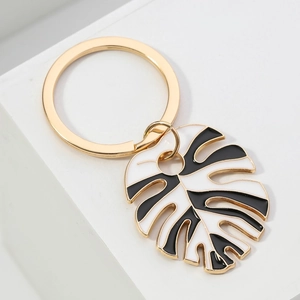 Golden monstera leaf keychain with black and white enamel finish for bag decoration