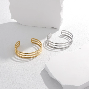 Detail of parallel hollow lines on gold and silver stainless steel open bangles