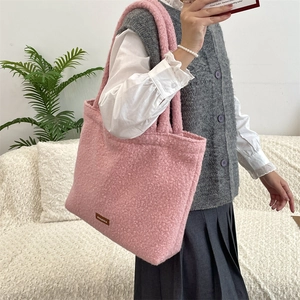 Dettaglio della borsa tote rosa in pile con logo in pelle marrone e tracolla larga