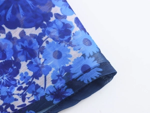 Detailed macro shot of floral chiffon fabric with elegant blue prints and stitched edges