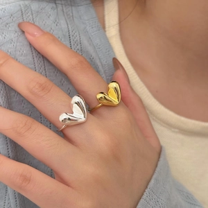 Detailed view of 3D heart-shaped silver and gold rings worn on fingers with modern design