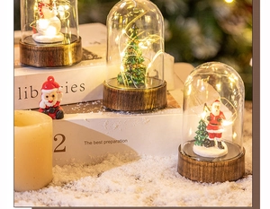 Close-up of lighted Christmas snow globe lanterns with LED trees and Santa on faux snow