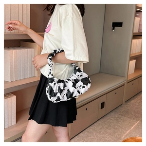 Close-up of cloud bag featuring cow print pattern and stylish ruched handle detail