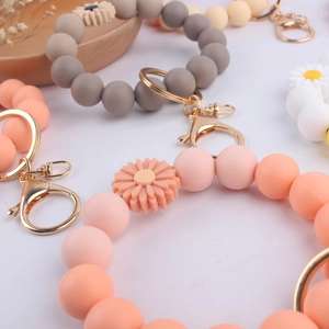 Detail of macaron silicone bead keychains with daisy accents and golden metal clasps