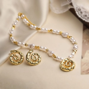 Vintage pearl necklace and spiral gold earrings jewelry set on elegant beige silk fabric