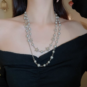 Close-up of layered silver star necklace with grey pearls on model neck