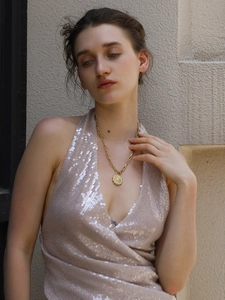 Detail of 18K gold plated north star coin pendant on a chunky chain worn by a model