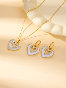 Detail of gold heart necklace and earrings set with shimmering shell inlay and crystals