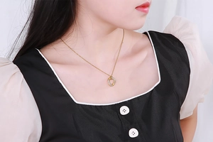 Close-up of golden hollow horseshoe pendant with sparkling diamonds on a model