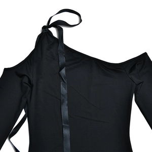 Detalle de mono negro de un hombro con manga larga y elegante lazo anudado en el hombro