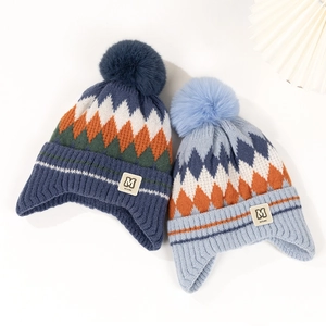 Detail of winter knitted baby hats with earflaps, pom-poms, and diamond patterns