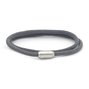 Macro shot of grey woven cord bracelet featuring a magnetic silver metal cylinder clasp