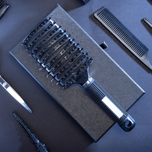 Curved vented hair brush with boar bristles and nylon pins on black textured box