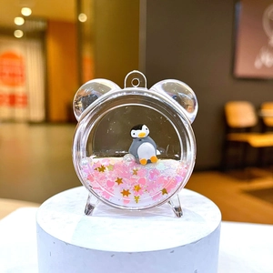 Detail of penguin charm with pink heart sequins in acrylic clock-shaped bottle