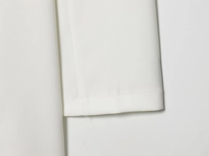 Detailed macro view of white fabric texture and premium stitching on the elegant skirt hem