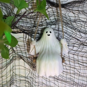 Detailed close-up of a resin ghost sitting on a swing for Halloween garden tree decoration