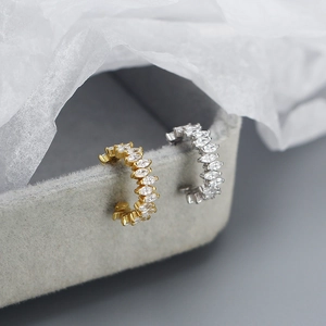 Detail of zircon marquise cuff earrings in gold and silver finish on a jewelry box