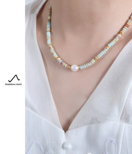 Detail of colorful beads and white pearl on stainless steel necklace worn by a model