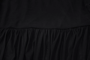 Close-up of black mesh fabric detail showing pleated texture and refined stitching on dress