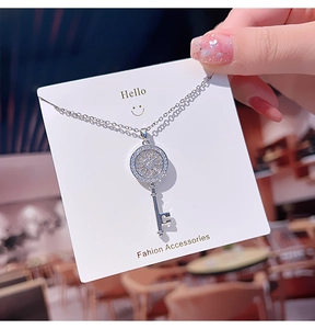 Macro detail of silver key pendant with radial zircon inlay on a minimalist O-chain
