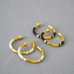 Macro detail of enamel gold-plated C-shaped earrings with black and white texture