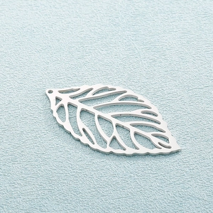Macro shot of silver cutout leaf pendant in stainless steel on a blue texture background