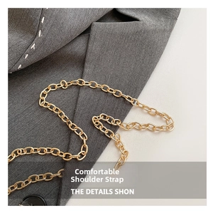 Close-up of a premium gold metal chain strap on a grey textured suit fabric background