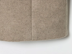 Detailed macro view of high-quality wool blend fabric and premium stitching on camel coat