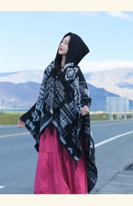 Close-up of ethnic black hooded poncho with geometric patterns and fringe detail