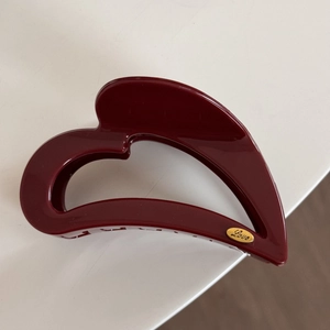Detailed view of large dark red heart-shaped hair claw with gold Love engraved charm