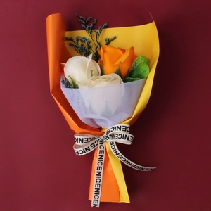 Detail of handmade orange and cream soap roses bouquet with branded decorative ribbon