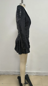 Détail d'un ensemble de costume à paillettes noires avec blazer et jupe plissée sur mannequin