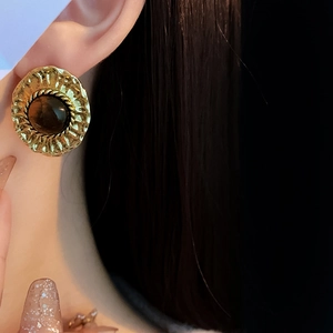 Gros plan détaillé d'une boucle d'oreille vintage dorée avec pierre œil de tigre