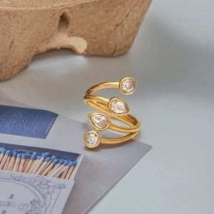 Macro detail of a spiral gold-plated ring featuring zircon pear and round cut stones