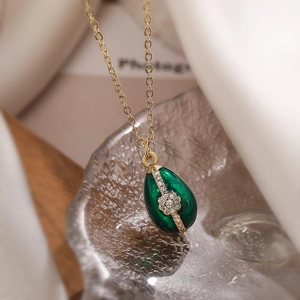 Dettaglio collana in oro con ciondolo a goccia verde su cubetti di ghiaccio in vetro