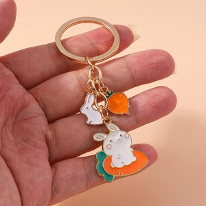 Cute bunny and carrot keychain accessory with gold metal clip on peach background
